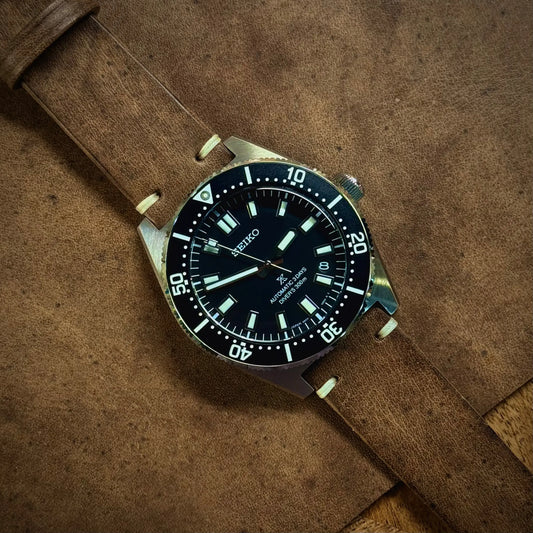 Watch with a brown leather strap on a brown textured background