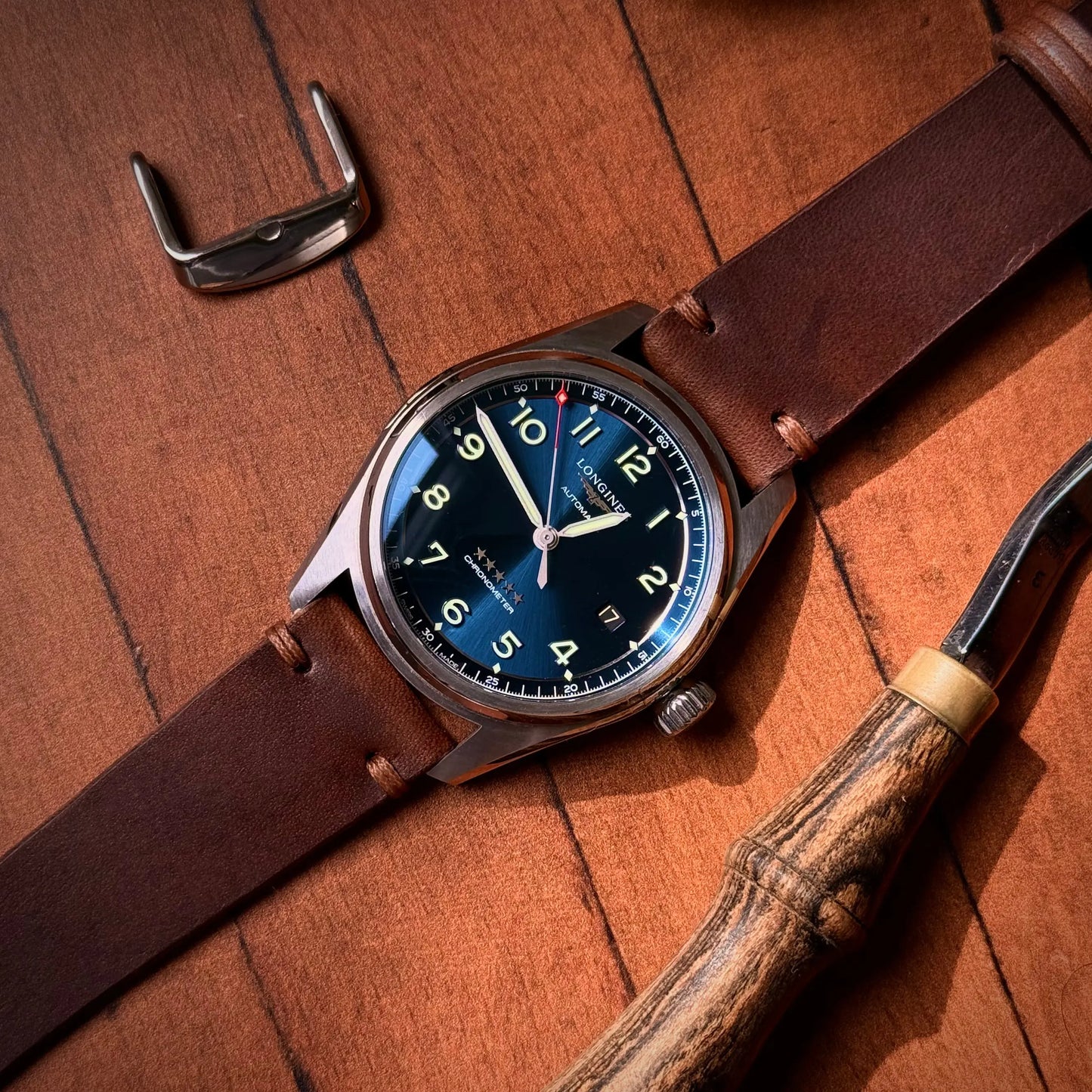 Watch with brown leather strap and blue dial on wooden surface