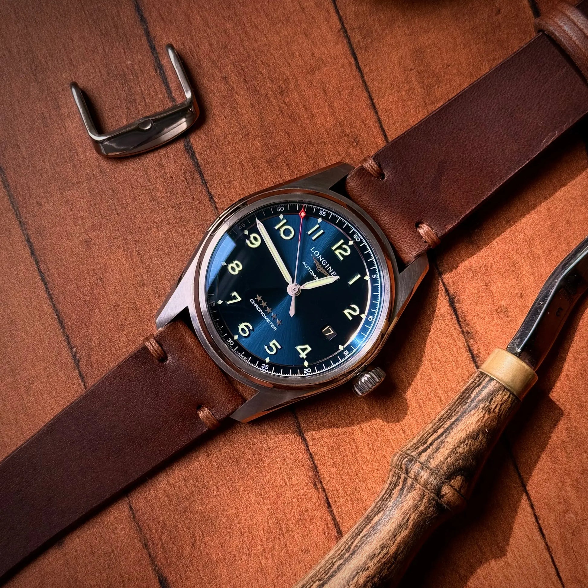 Watch with brown leather strap and blue dial on wooden surface