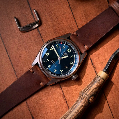 Watch with brown leather strap and blue dial on wooden surface